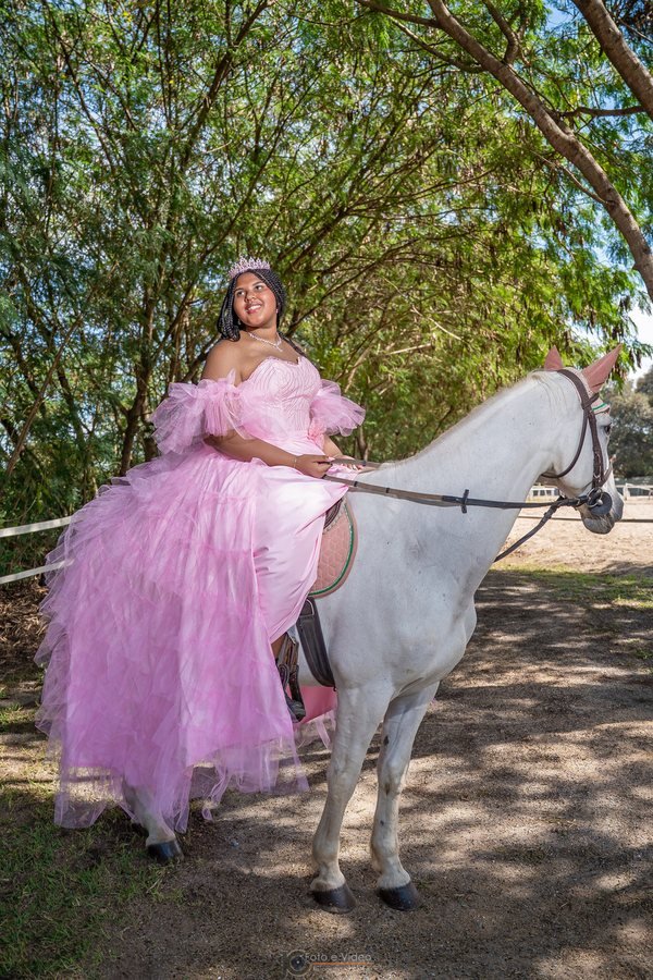 Ester Zion com vestido rosa ao lado de um cavalo branco
